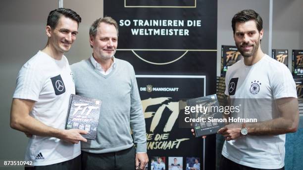 Nicklas Dietrich and Yann-Benjamin Kugel , fitness coaches of Germany, pose with publisher Stefan Weikert during the 'Fit wie die Mannschaft' Book...