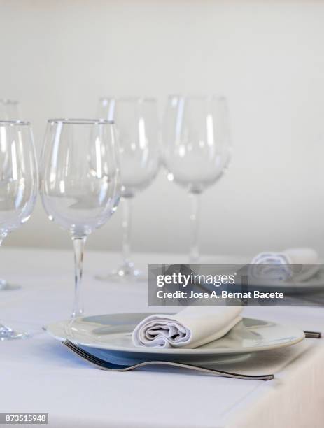 restaurant table prepared with white tablecloth, napkins, cutlery and wine glasses, with wooden chairs on a white background - la belle équipe restaurant stock pictures, royalty-free photos & images