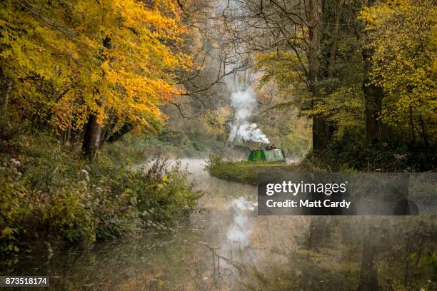 Smoke from a wood burner rises from a narrowboat moored on the Kennet and Avon canal near the Dundas Aqueduct as the sun rises on November 13, 2017...