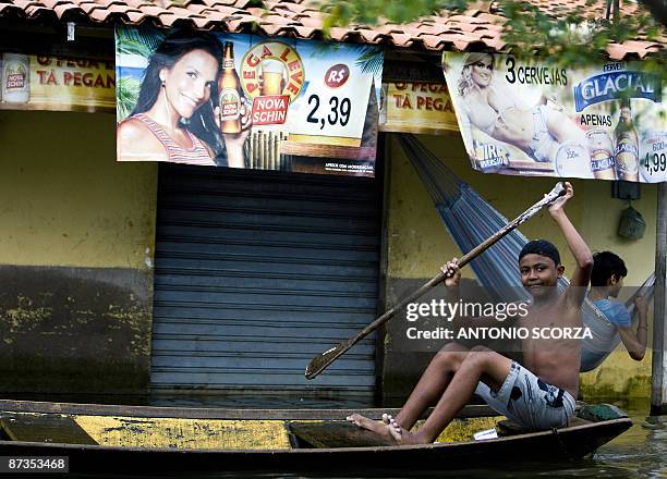 Boy rows a canoe in a street flooded by the Mearim river in Bacabal, in the state of Maranhao, northern Brazil, on May 15, 2009. Around a million...