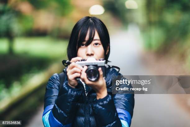 junge frau mit kamera in der natur - spiegelreflexkamera stock-fotos und bilder