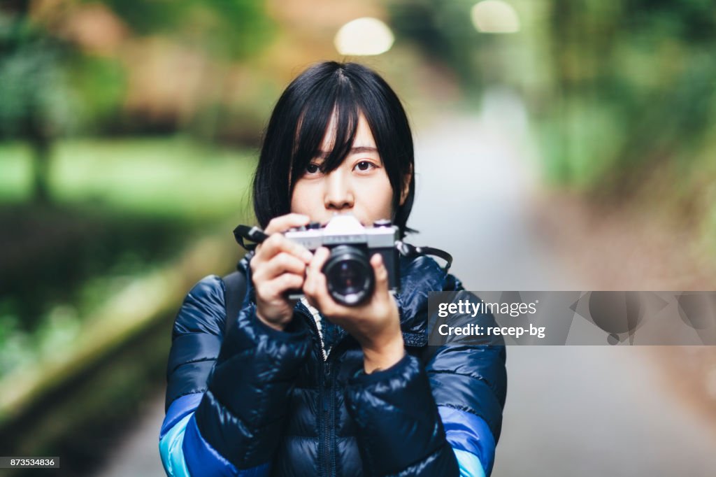 Joven mujer sosteniendo la cámara en la naturaleza