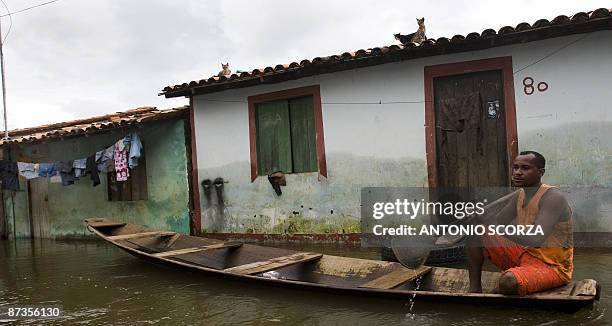 Man rows a canoe while cats remain on the roof of a house in a street flooded by the Mearim river in Bacabal, in the state of Maranhao, northern...