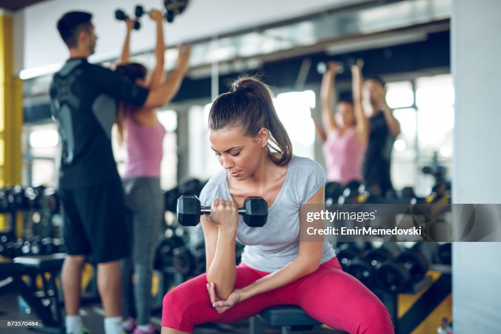 Young sporty woman doing dumbbell exercise at the gym.