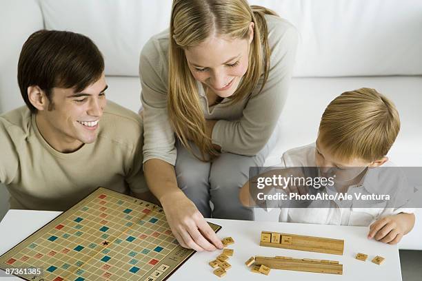 family playing board game together, mother arranges game pieces - jogo de palavras imagens e fotografias de stock
