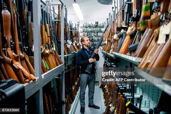 A firearms inspector poses for a photograph with seized and handed in ...