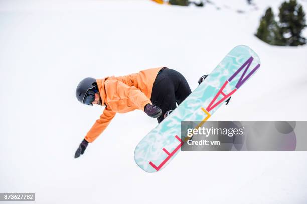 female snowboarder in mid-air - freestyle snowboarding stock pictures, royalty-free photos & images