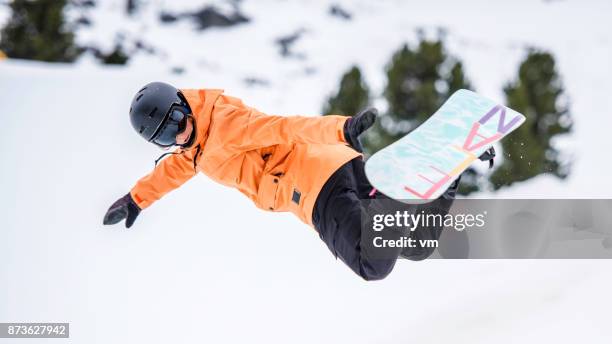 female snowboarder in mid-air reaching for a grab - freestyle snowboarding stock pictures, royalty-free photos & images