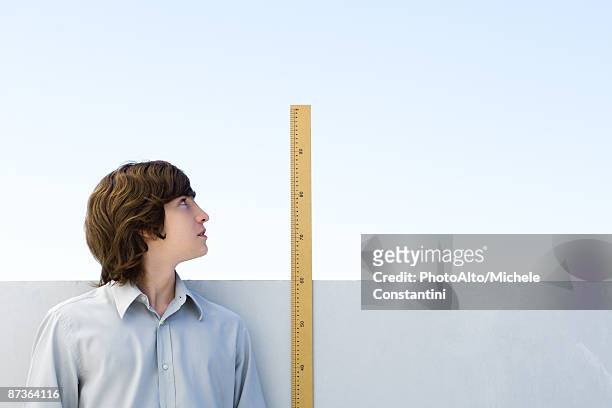 young man measuring his height with ruler - height fotografías e imágenes de stock