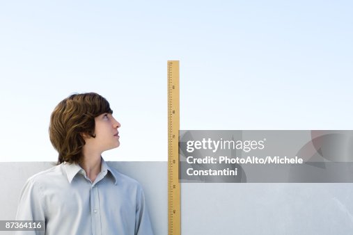 Young man measuring his height with ruler Young man measuring his height with ruler