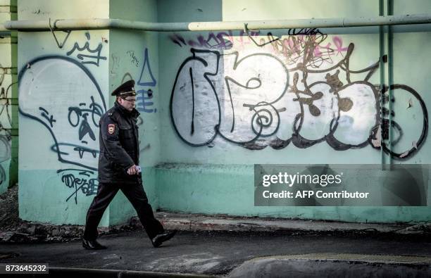 Policeman walks past a graffiti-covered wall in the southern Russian city of Krasnodar on November 13, 2017. / AFP PHOTO / Mladen ANTONOV