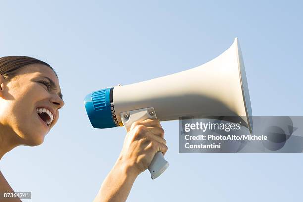 woman shouting into megaphone, low angle view, cropped - megafon stock-fotos und bilder