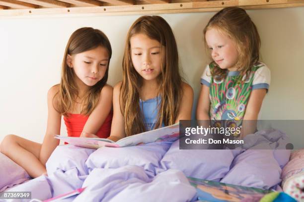young girls reading story on bunk bed - bunk beds for 3 stock-fotos und bilder
