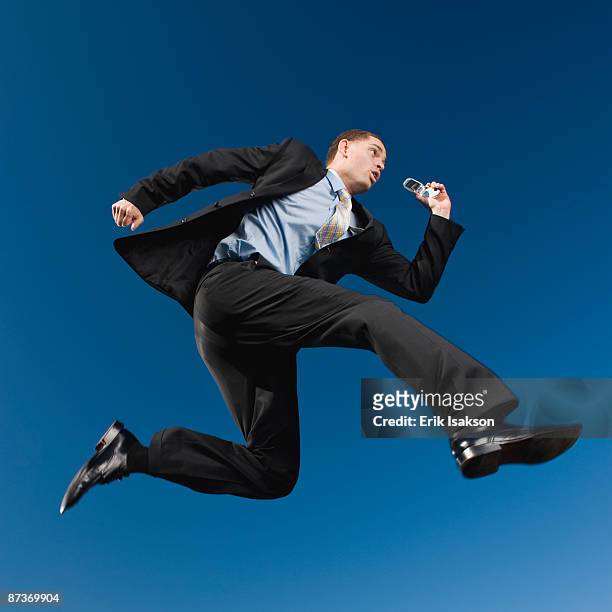 african businessman in mid-air holding cell phone - jumping ストックフォトと画像