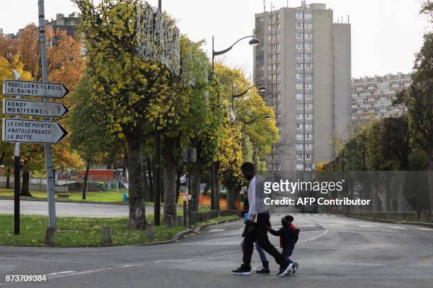 People walk past apartment buildings, part of the Chene Pointu housing estate, on November 13 in Clichy-sous-Bois, northern Paris. / AFP PHOTO /...