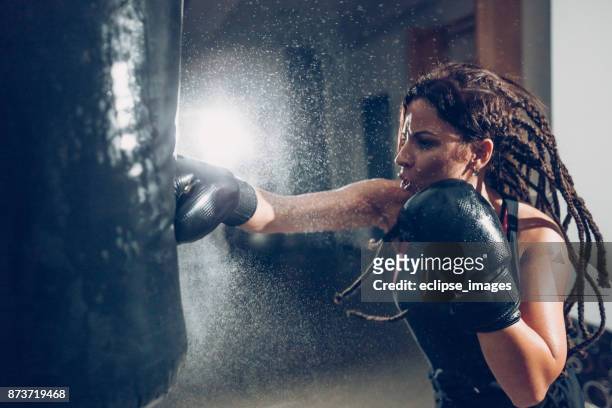 vrouwelijke kickbokser training aan een bokszak - woman gym boxing stockfoto's en -beelden