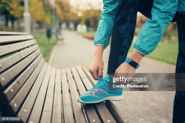 woman tying up her shoe lace - tennis shoe stock pictures, royalty-free photos & images