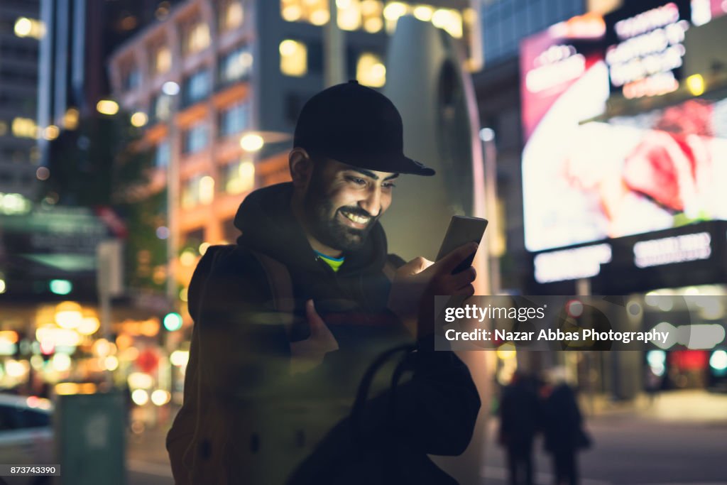 Young man using smart device to navigate through city.