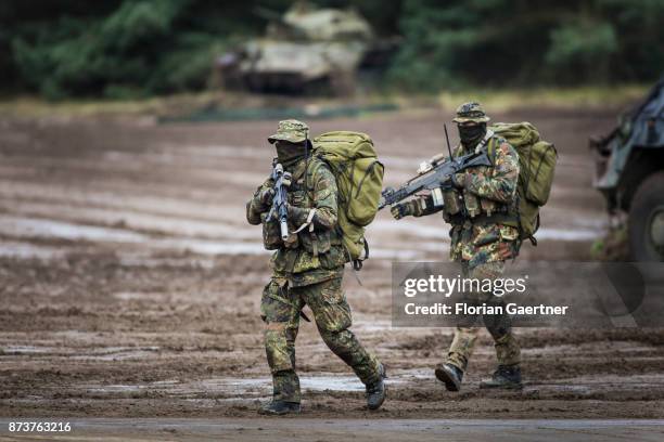 Two masked soldiers from the patrol with backpacks and guns. Shot during an exercise of the land forces on October 13, 2017 in Munster, Germany.