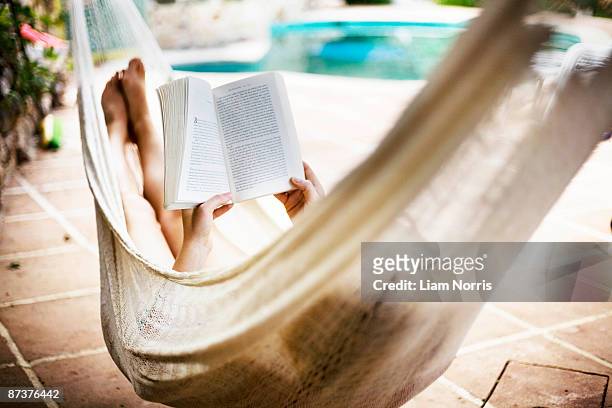 a woman asleep in a hammock - lezen stockfoto's en -beelden