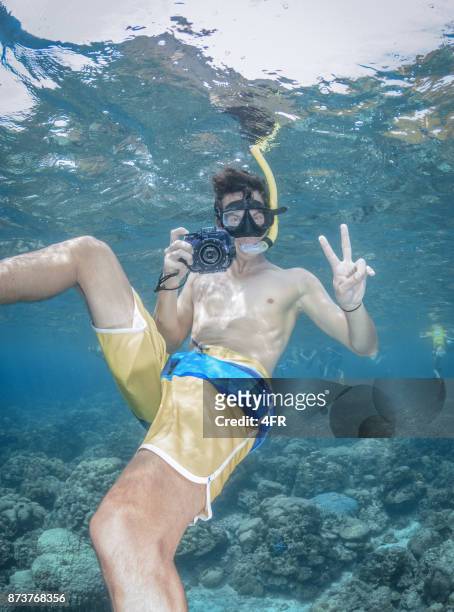 uomo libero immersioni con la sua fotocamera subacquea, gesto candido e sorriso - macchina fotografica subacquea foto e immagini stock