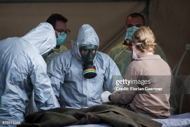 Two medical professionals wearing protective suits and gas masks treat a soldier. Shot during an exercise of the land forces on October 13, 2017 in...