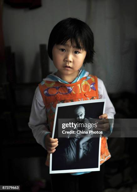 Earthquake survivor Gan Yu who is a student from the Lele Kindergarten of Yongxing Township, holds a photograph taken several days after the...