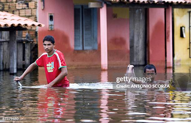 Two residents cross a street flooded by the Mearim river in Bacabal, in the state of Maranhao, northern Brazil, on May 15, 2009. Some 1,115 million...