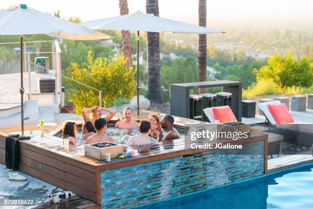 friends relaxing in a luxury hot tub outdoors at sunset - hot tub party stock pictures, royalty-free photos & images