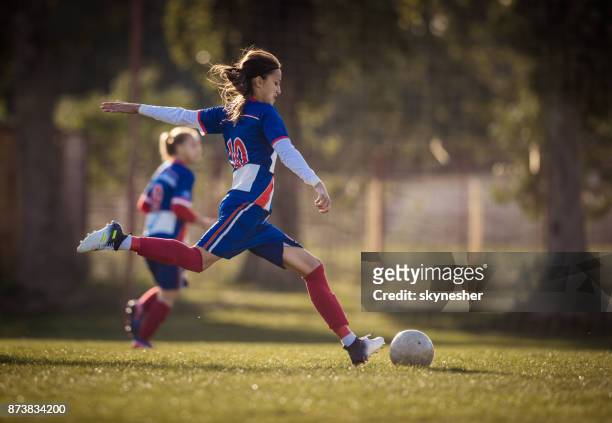 teenage soccer player in action on a playing field. - shooting football stock pictures, royalty-free photos & images
