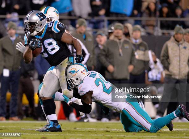 Reshad Jones of the Miami Dolphins tackles Jonathan Stewart of the Carolina Panthers during their game at Bank of America Stadium on November 13,...