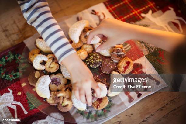 two children choosing traditional german christmas cookies - eating cookies stock-fotos und bilder