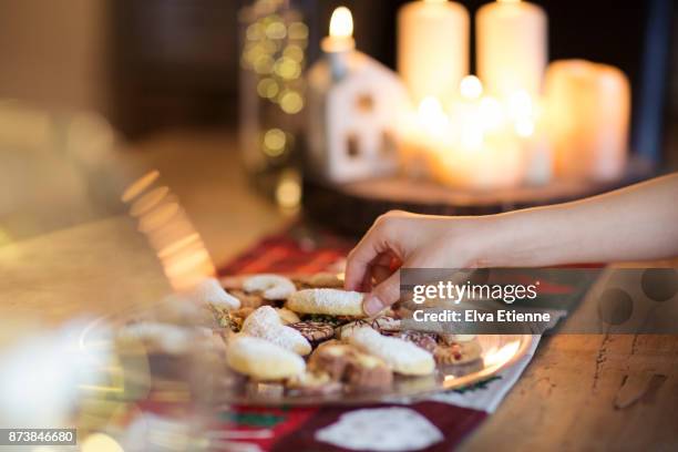 child taking a traditional german christmas cookie off a plate on a table - icing sugar stock pictures, royalty-free photos & images