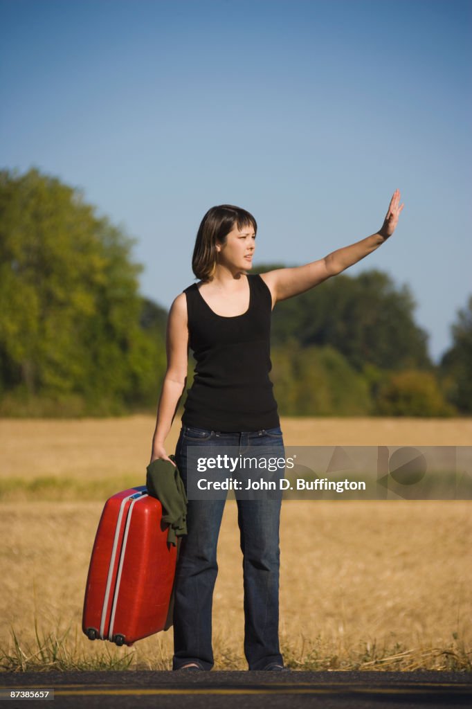 Asian woman carrying suitcase on roadside