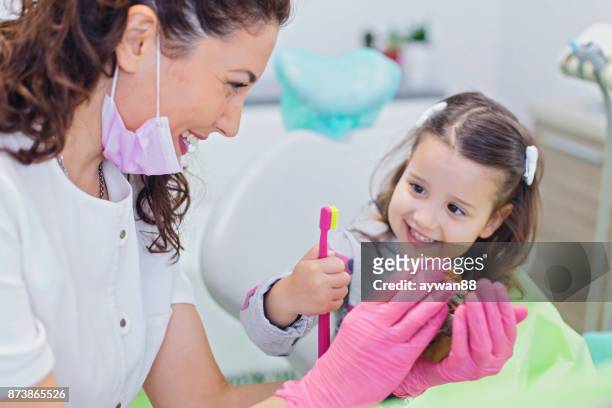 dentista enseñanza a linda chica sobre higiene oral - odontopediatría fotografías e imágenes de stock