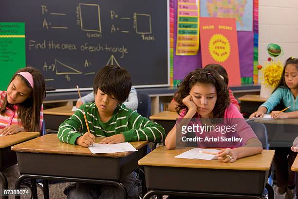 students taking test in classroom - sad children only stock pictures, royalty-free photos & images