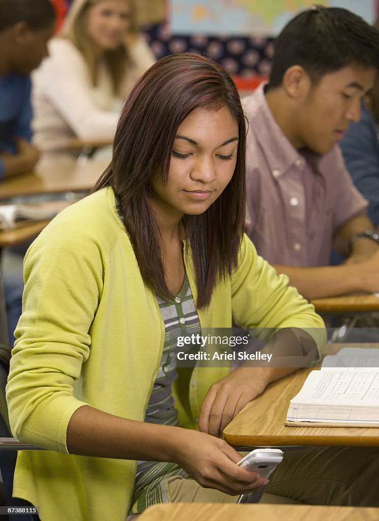 Teenage girl text messaging on cell phone in classroom