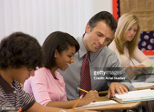 teacher helping student with homework in classroom - tuition assistance stock pictures, royalty-free photos & images