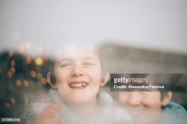 happy kids at christmas, looking through window - alexandra pavlova foto e immagini stock