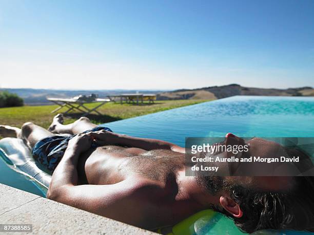 man resting in swimming pool - david de lossy sleep stock pictures, royalty-free photos & images