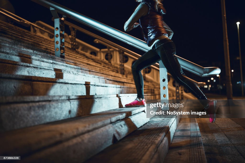 Young woman running at night in a urban city area