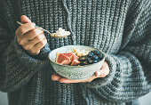 Woman in woolen sweater eating rice coconut porridge