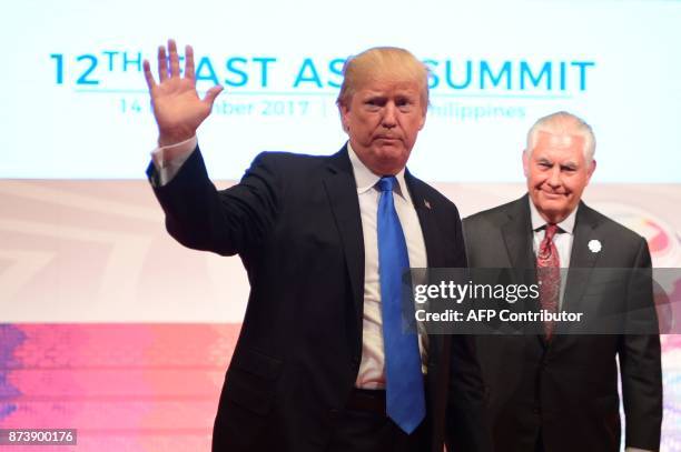 President Donald Trump waves as US Secretary of State Rex Tillerson looks on after attending the 31st Association of Southeast Asian Nations Summit...