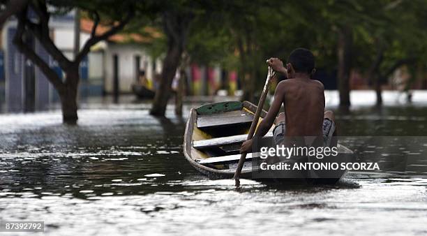 Boy rows a canoe in a street flooded by the Mearim river in Bacabal, in the state of Maranhao, northern Brazil, on May 15, 2009. Around a million...