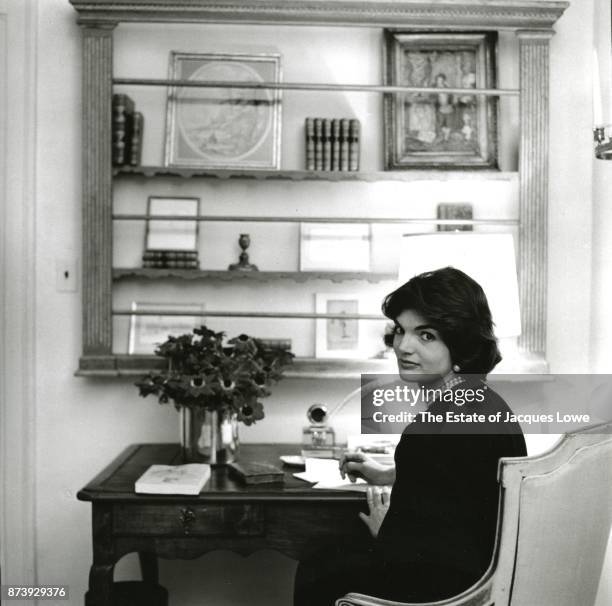 Portrait of Jacqueline Kennedy seated at a desk as she looks over her shoulder in her townhouse in the Georgetown neighborhood, Washington DC, Fall...