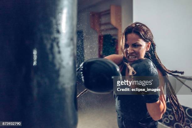 kickboxer hembra capacitación con una bolsa de boxeo - combat sport fotografías e imágenes de stock