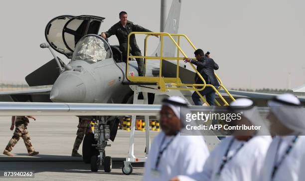 Emiratis walk past a French Rafale fighter jet displayed during the Dubai Airshow on November 14 in the United Arab Emirates. / AFP PHOTO / KARIM...