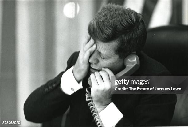 In the Oval Office, US President John F Kennedy holds his hand to his head as he is informed via telephone of Patrice Lumumba's assassination,...