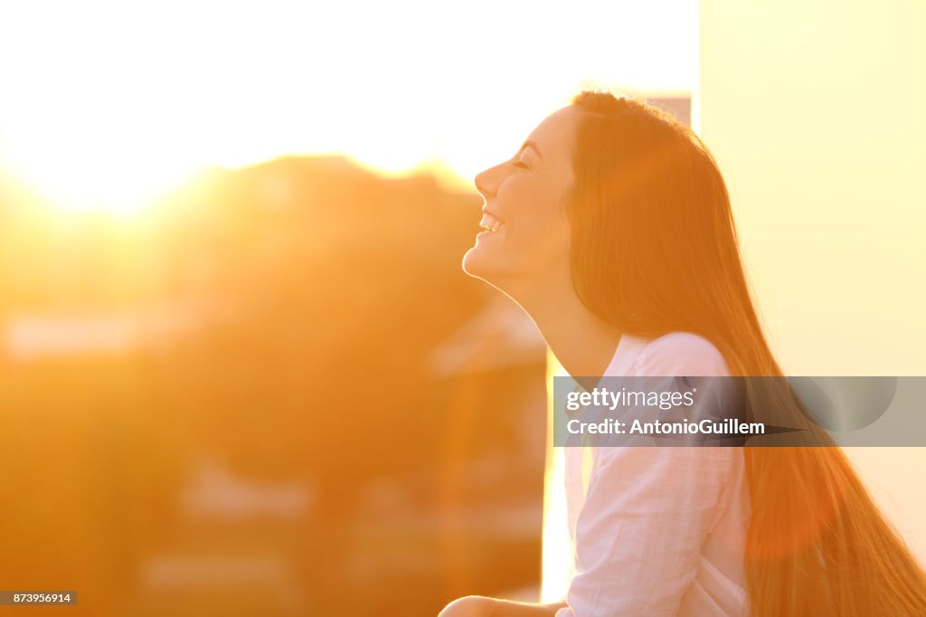 Frau, die Atmung bei Sonnenuntergang in einen Balkon