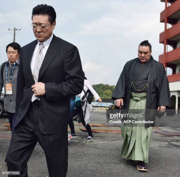 Mongolian sumo wrestler yokozuna, or grand champion, Harumafuji and stable master Isegahama walk towards a dormitory in Tagawa city, Fukuoka...